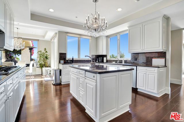 a kitchen with kitchen island granite countertop a stove top oven a sink and dishwasher with wooden floor