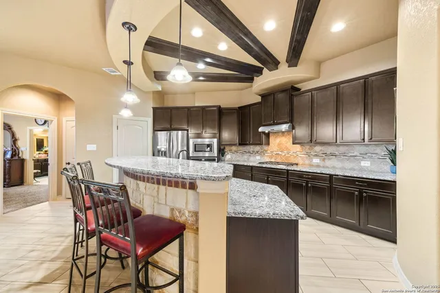 a kitchen with stainless steel appliances kitchen island granite countertop a table chairs in it and wooden floors