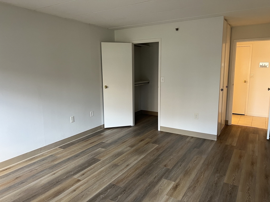 1 Pond Street, Unit 8K Winthrop, MA 02152 - Photo 11 of 14 a view of an empty room with wooden floor and a window