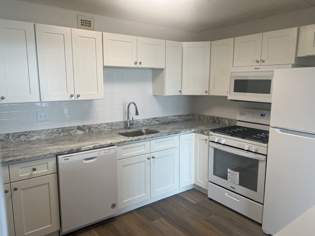1 Pond Street, Unit 8K Winthrop, MA 02152 - Photo 5 of 14 a kitchen with granite countertop white cabinets and white appliances