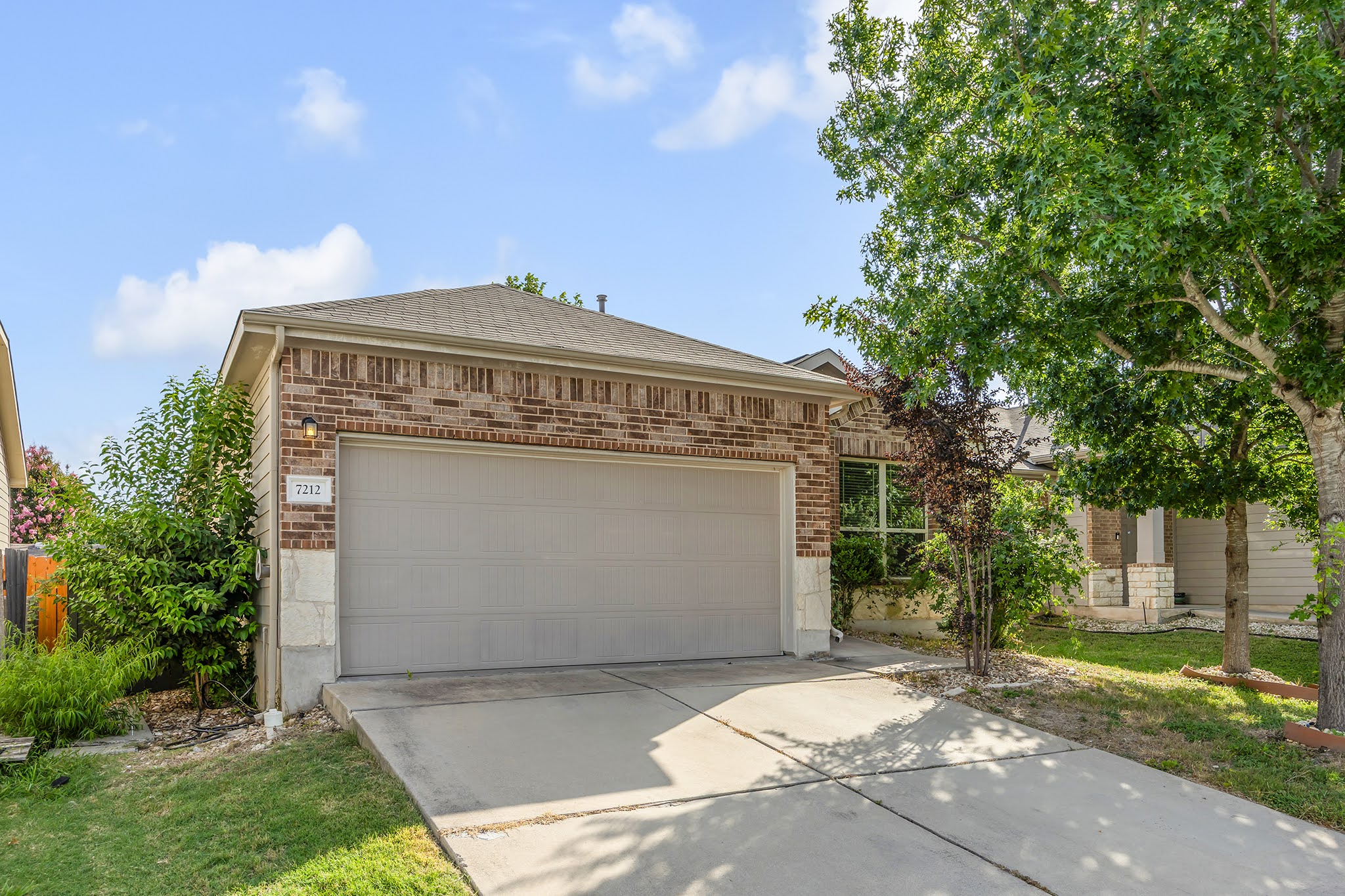 7212 Vail Ridge Street Austin, TX 78744 - Photo 22 of 26 A classic brick and stone facade welcomes with an integrated garage and a verdant, mature front yard.