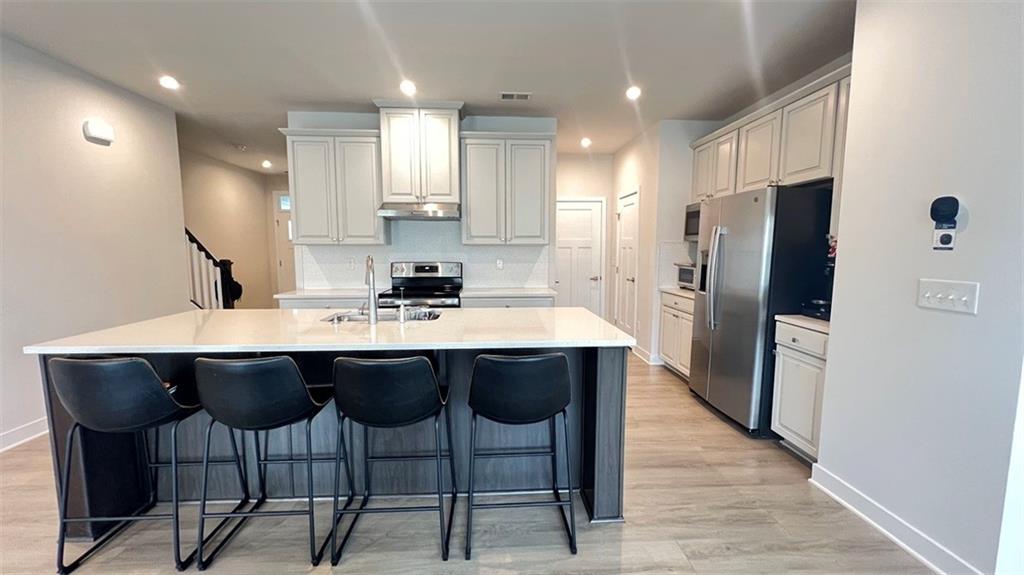136 Salt Lk Lane Hoschton, GA 30548 - Photo 4 of 22 a kitchen with a dining table chairs refrigerator and microwave