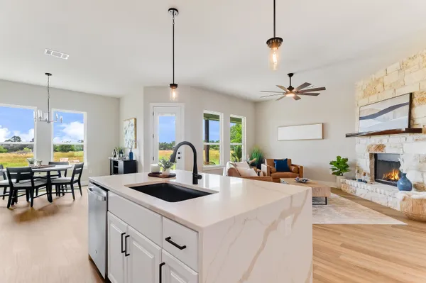 a kitchen with a stove a center island a dining table wooden floor and a fireplace
