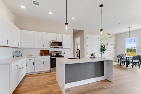 a large kitchen with stainless steel appliances kitchen island granite countertop a sink a counter space and cabinets