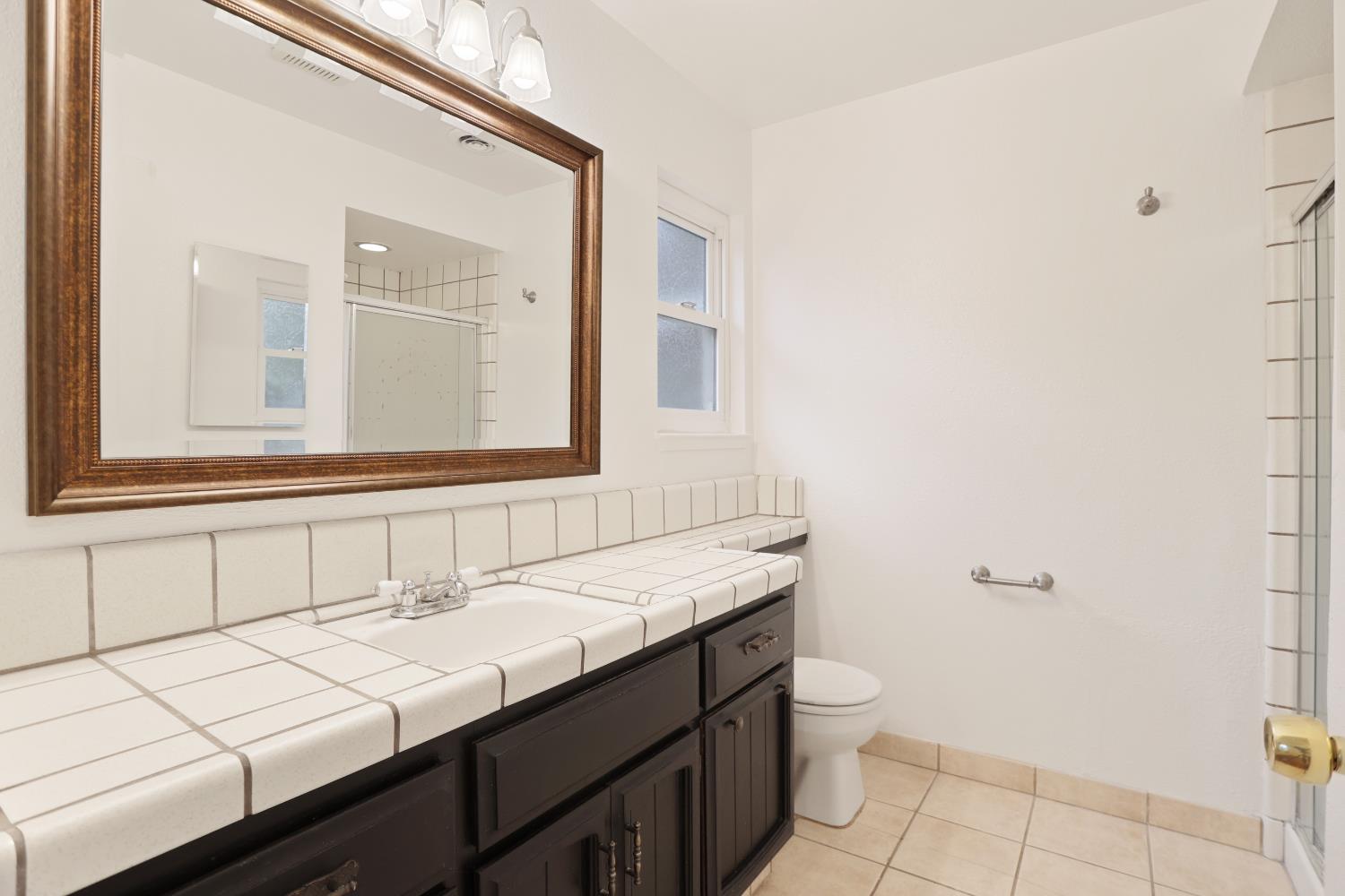 1417 Fransen Lane Modesto, CA 95355 - Photo 21 of 30 a bathroom with a granite countertop sink a toilet and a mirror