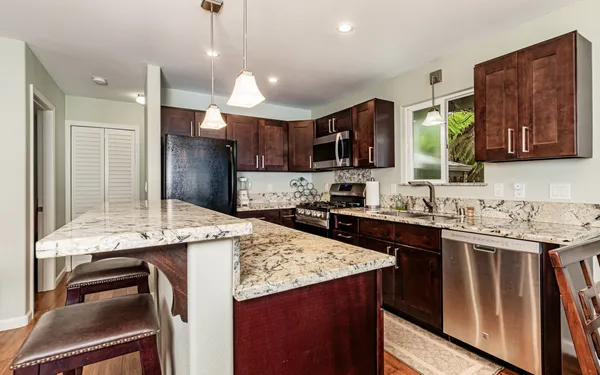 a kitchen with kitchen island granite countertop a sink stove and refrigerator