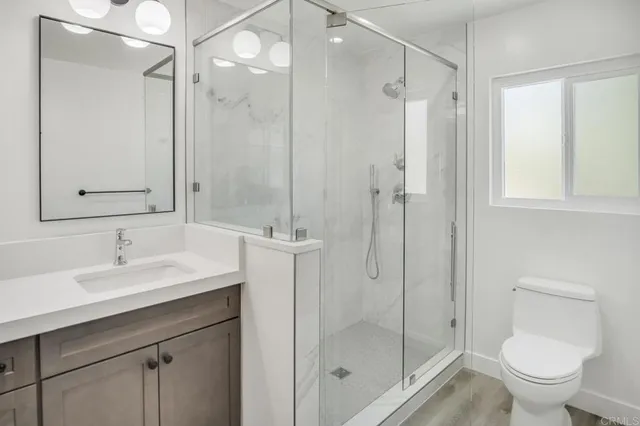 a bathroom with a shower sink vanity mirror and toilet