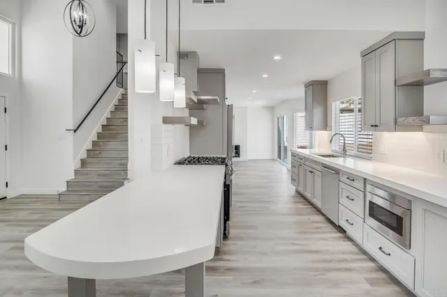 a large kitchen with stainless steel appliances kitchen island wooden floors granite top and stainless steel appliances