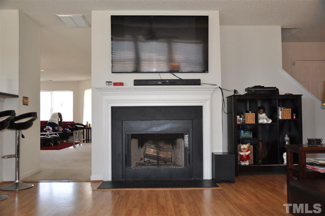 3305 Marcony Way Raleigh, NC 27610 - Photo 13 of 25 a living room with a fireplace a flat screen tv and a book shelf
