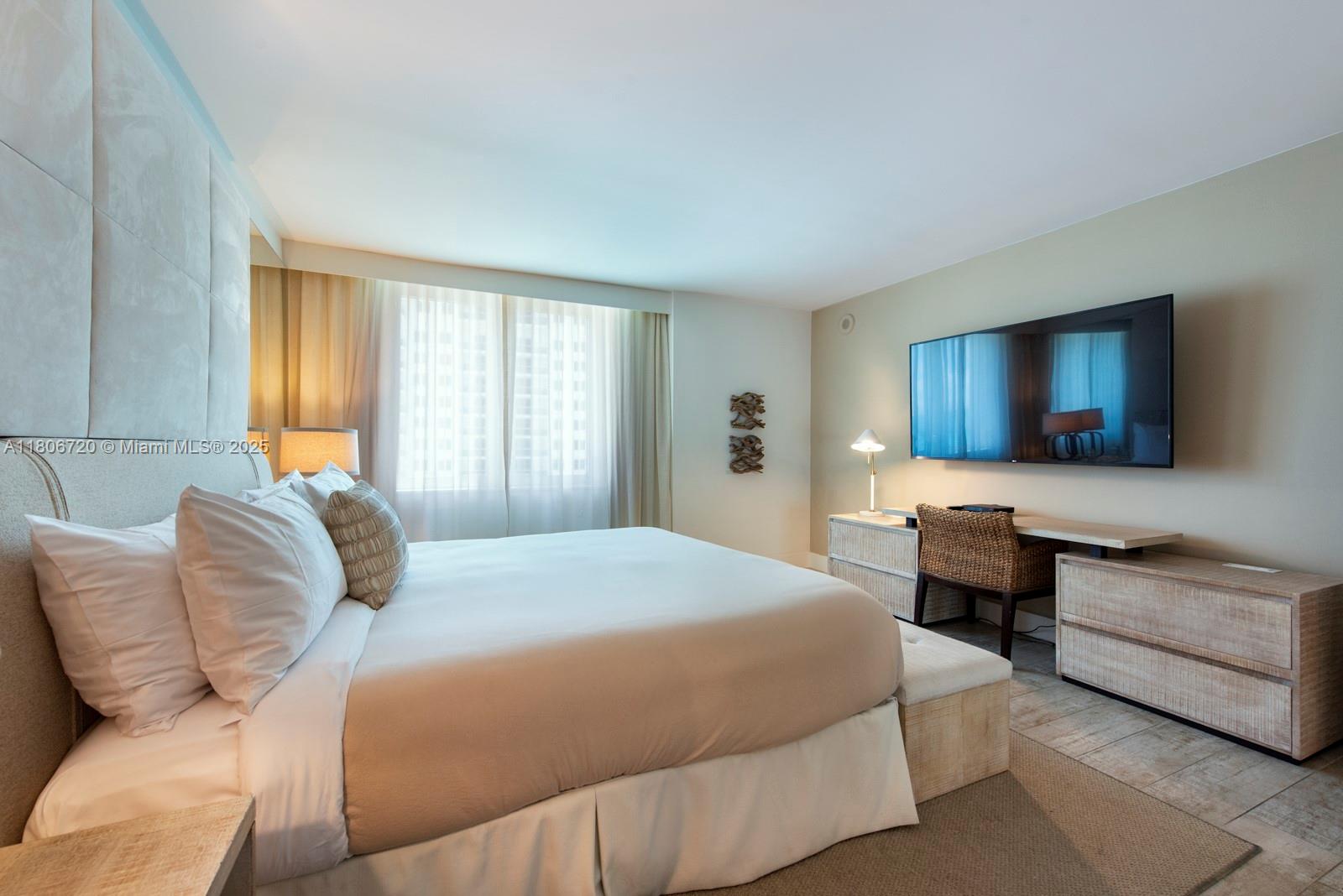 102 24th Street, Unit 1012 Miami Beach, FL 33139 - Photo 14 of 18 a bedroom with a large bed couch and a flat screen tv