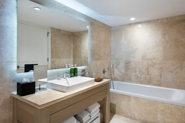 a bathroom with a sink a large mirror and a bathtub