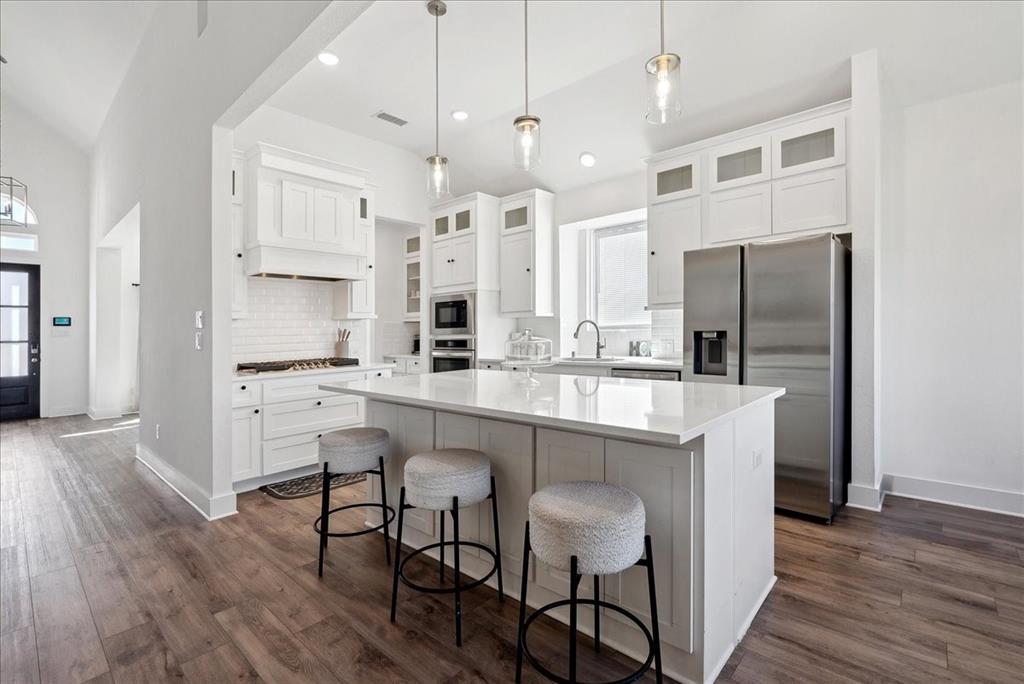 1710 Highwood Road Forney, TX 75126 - Photo 7 of 25 Modern kitchen featuring a white subway tile backsplash, stainless steel appliances, and a central island with a solid surface countertop