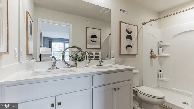 a bathroom with a sink toilet double vanity and shower