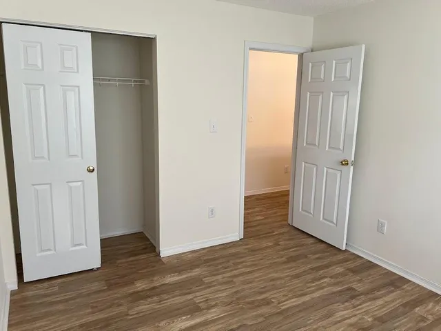 an empty room with wooden floor and closet area