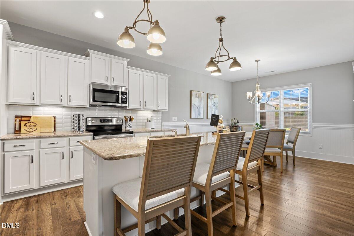 88 Heath Road Lillington, NC 27546 - Photo 39 of 54 a kitchen with stainless steel appliances granite countertop a dining table chairs refrigerator and microwave