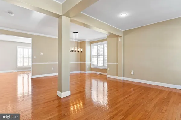 a view of an empty room with window and wooden floor