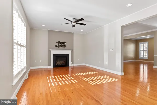 a view of a livingroom with wooden floor a ceiling fan and windows