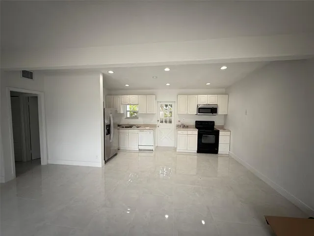 a view of kitchen with kitchen island a sink white cabinets and stainless steel appliances