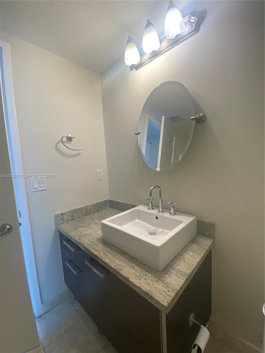185 Southwest 7th Street, Unit 4206 Miami, FL 33130 - Photo 7 of 26 a bathroom with a granite countertop sink and a mirror