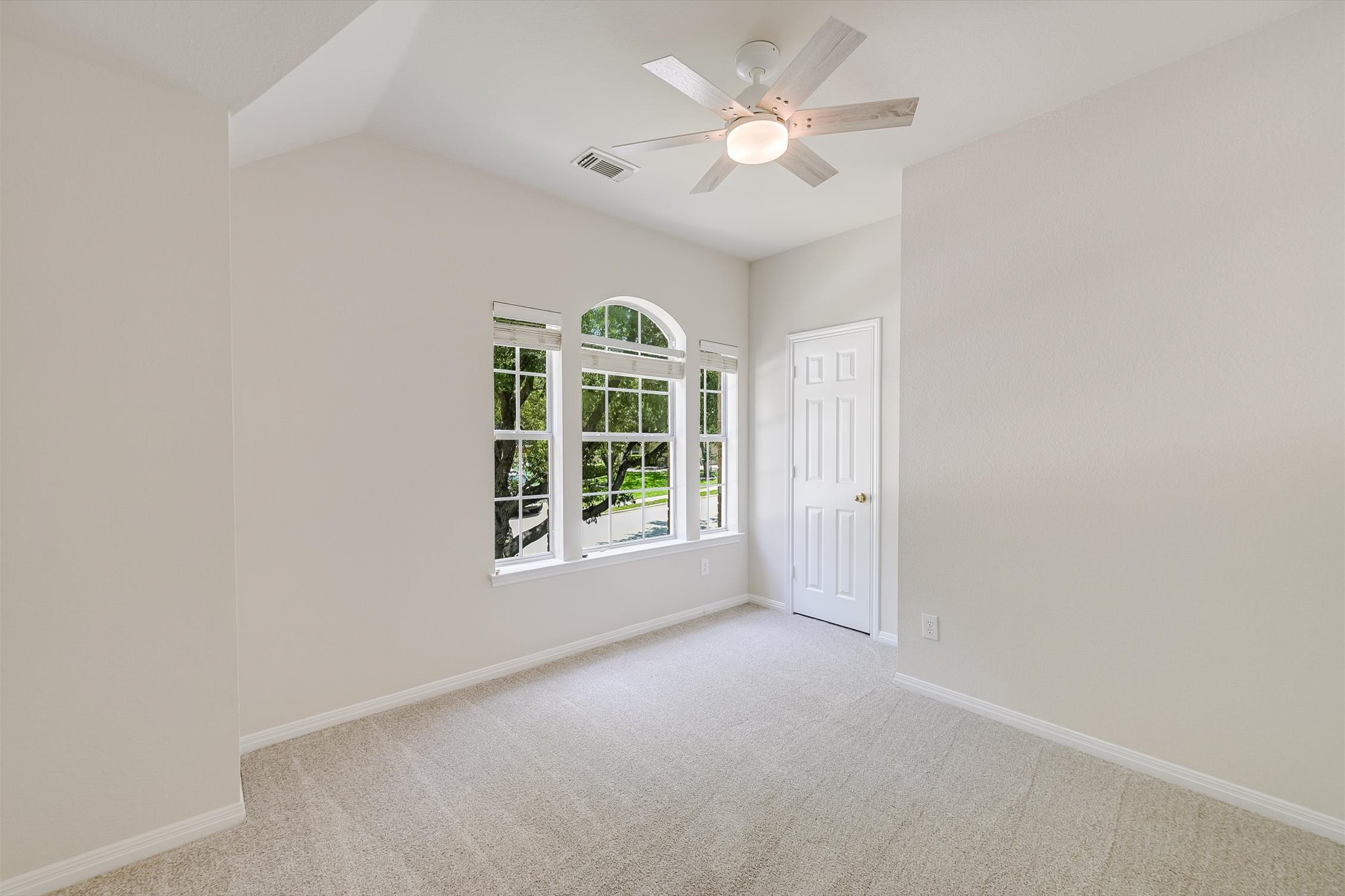 2849 Grimes Ranch Road Austin, TX 78732 - Photo 22 of 31 A well-lit bedroom with vaulted ceilings and a classic ceiling fan, offering tranquil outdoor views.