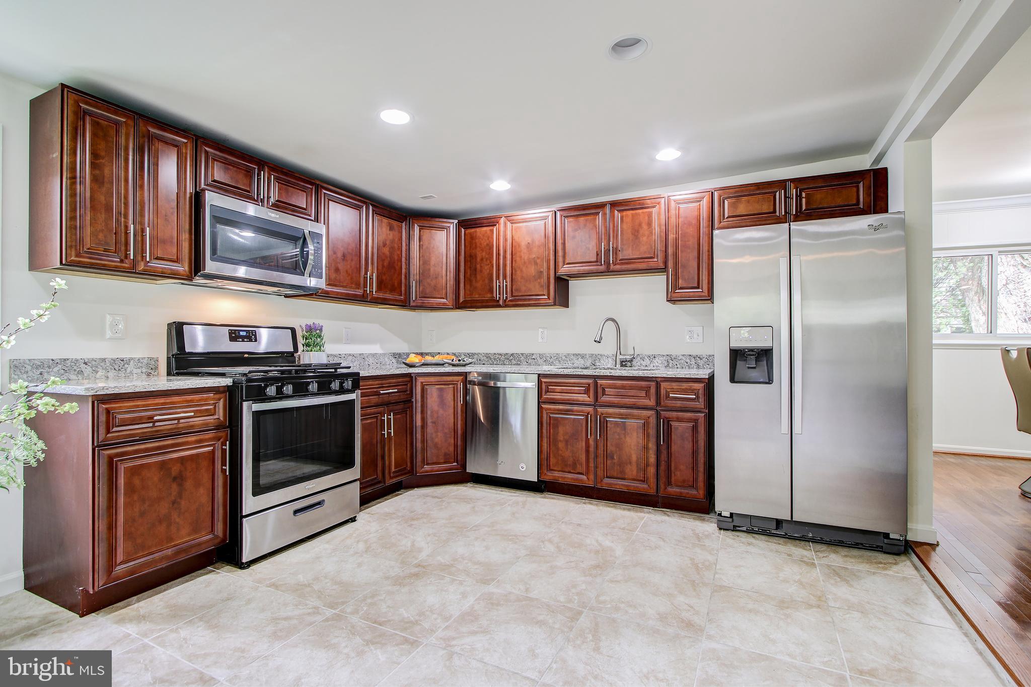 702 Dryden Street Silver Spring, MD 20901 - Photo 7 of 31 a kitchen with stainless steel appliances granite countertop a stove top oven a sink and dishwasher a refrigerator with wooden cabinets