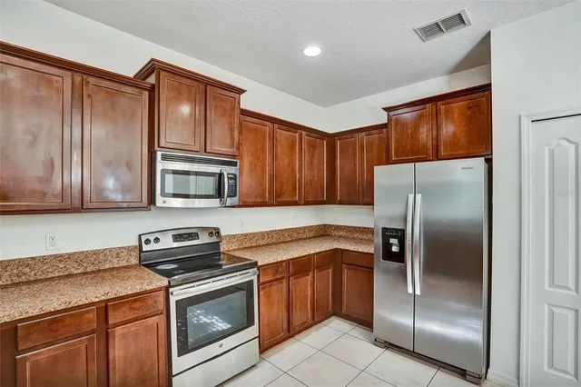 a kitchen with stainless steel appliances granite countertop a refrigerator a stove a sink and dishwasher