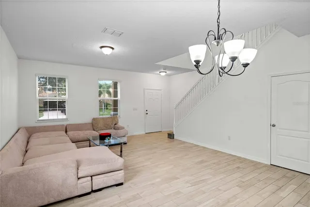 a living room with couches chandelier and kitchen view