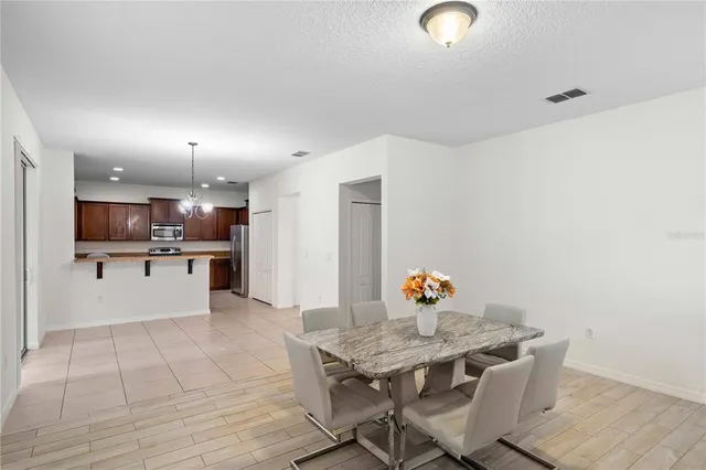 a kitchen with stainless steel appliances kitchen island granite countertop a dining table chairs and a refrigerator