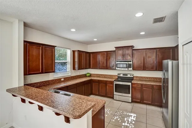 a kitchen with stainless steel appliances granite countertop a sink stove and refrigerator