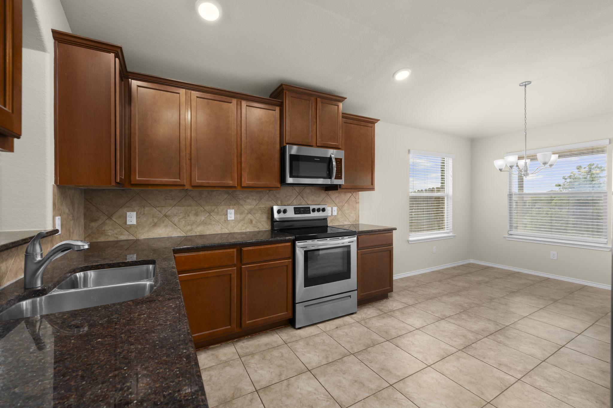 101 Plata Lane Jarrell, TX 76537 - Photo 15 of 27 a kitchen with granite countertop a stove top oven microwave and cabinets