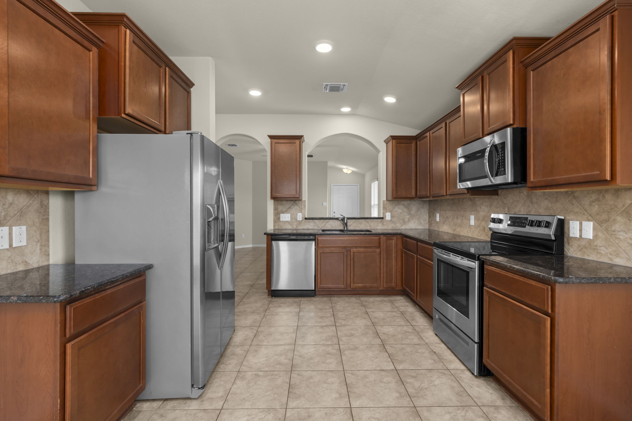 101 Plata Lane Jarrell, TX 76537 - Photo 17 of 27 a large kitchen with stainless steel appliances granite countertop a stove a sink dishwasher and a refrigerator