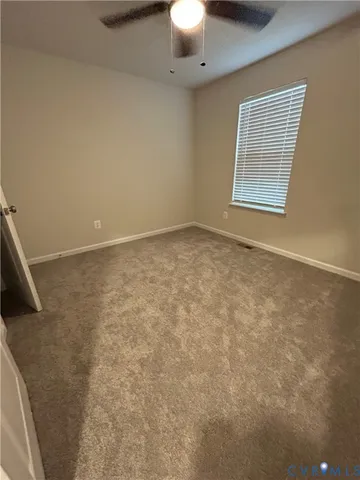 an empty room with a chandelier fan and windows