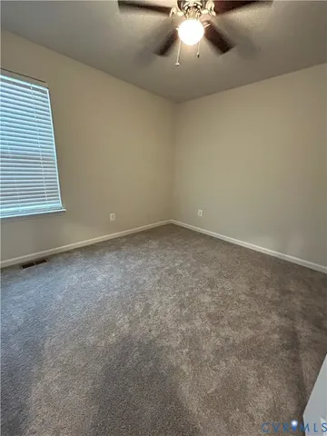 an empty room with a chandelier fan and window