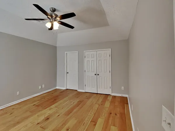 a view of a room with wooden floor and a ceiling fan