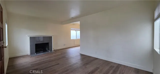 an empty room with wooden floor fireplace and windows
