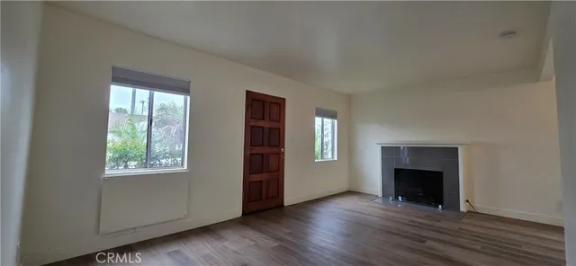 an empty room with windows a fireplace and wooden floor