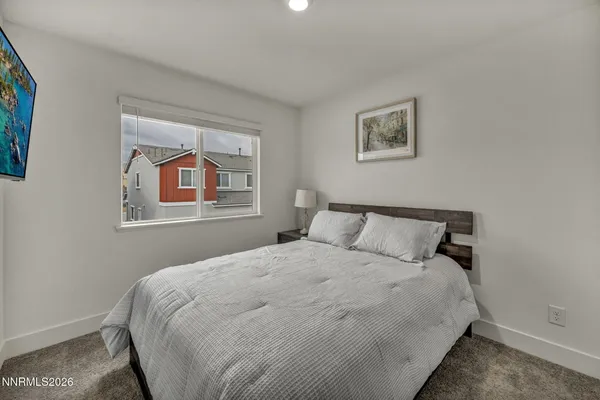 a bedroom with a bed and a large mirror next to a window