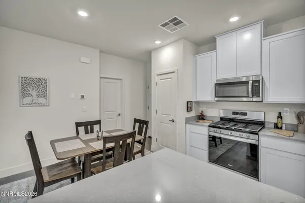 a kitchen with stainless steel appliances a stove a sink a microwave a dining table and chairs