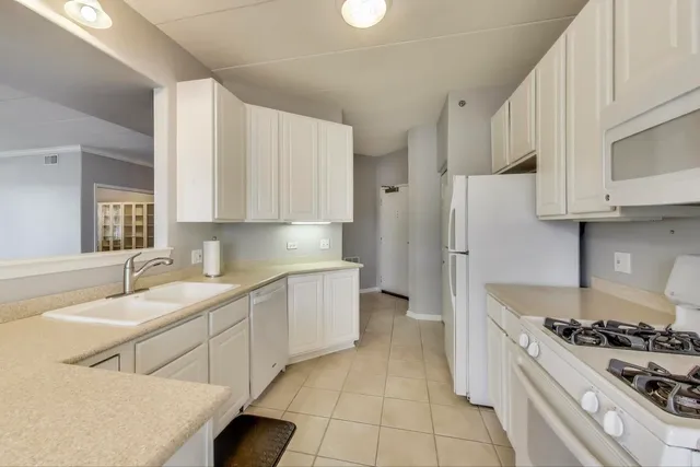 a large white kitchen with cabinets a sink a window and stainless steel appliances
