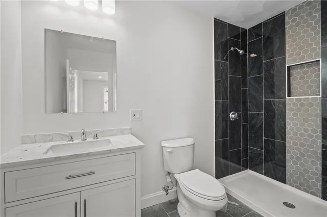a bathroom with a shower sink vanity mirror and toilet