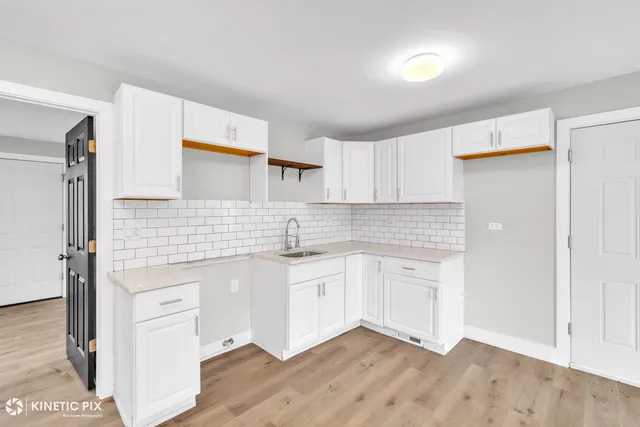 a kitchen with granite countertop white cabinets and wooden floor