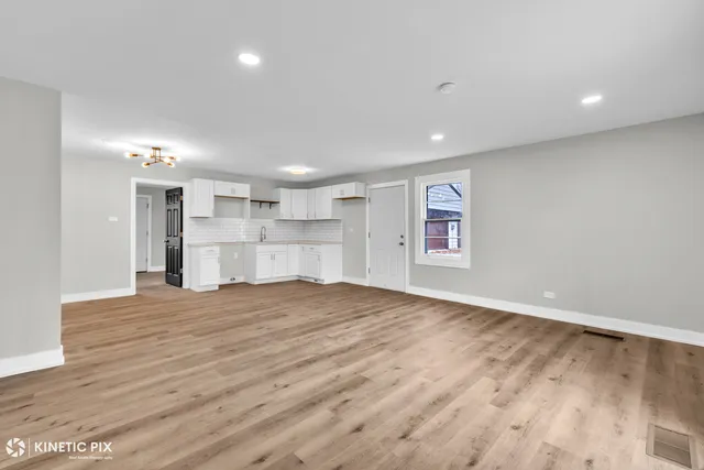 a view of empty room with kitchen and window