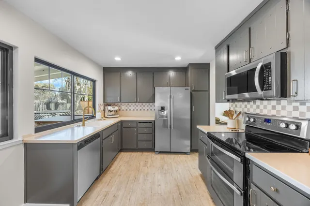 a large kitchen with a large window and stainless steel appliances