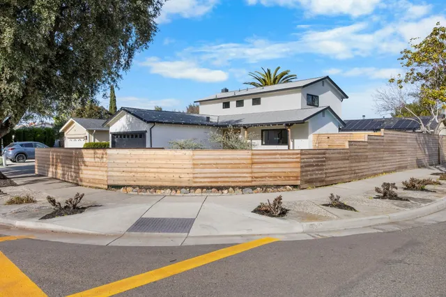 a white house with a large pool and lawn chairs under an umbrella
