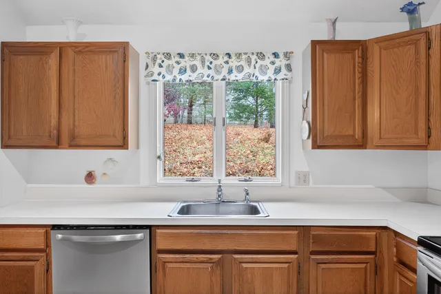 a kitchen with stainless steel appliances granite countertop a sink a window and cabinets