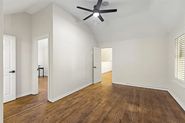 an empty room with wooden floor cabinet and windows