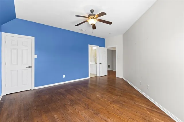 a view of an empty room with chandelier fan and wooden floor