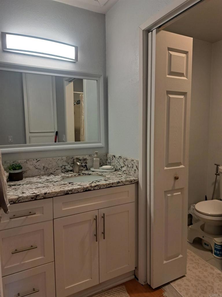 440 L Street, Unit J Chula Vista, CA 91911 - Photo 8 of 10 a bathroom with a granite countertop sink and a mirror