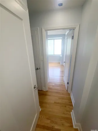 a view of a hallway with wooden floor and a bathroom