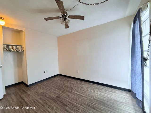 a view of room with hardwood floor and a ceiling fan